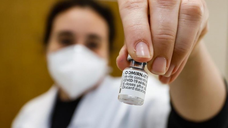 Uma profissional de saúde mostra um frasco de vacina. 