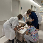 Três profissionais de saúde mexendo em caixas no corredor do Hospital de Clínicas, ao fundo, mais duas  profissionaismexem em  outras caixas