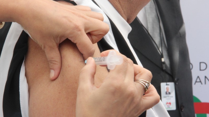 Uma profissional de saúde vacina o braço de uma mulher.