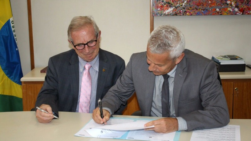 Presidente da Agers e Secretário Gabbardo olham para baixo enquanto o secretário assina o Termo. 