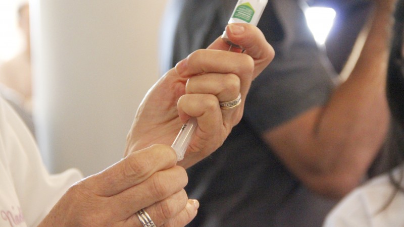 Mãos de uma mulher preparando uma vacina. 
